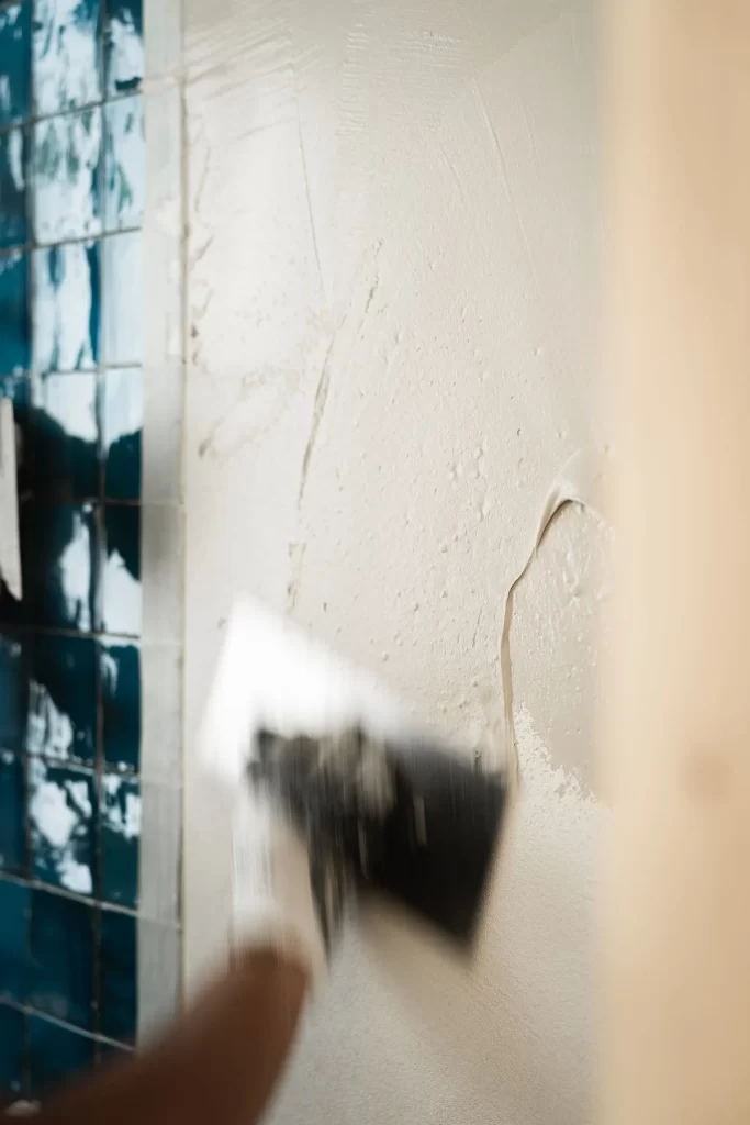 Aplicación de microcemento por un profesional en las paredes de un baño. Obra de reforma de la vivienda