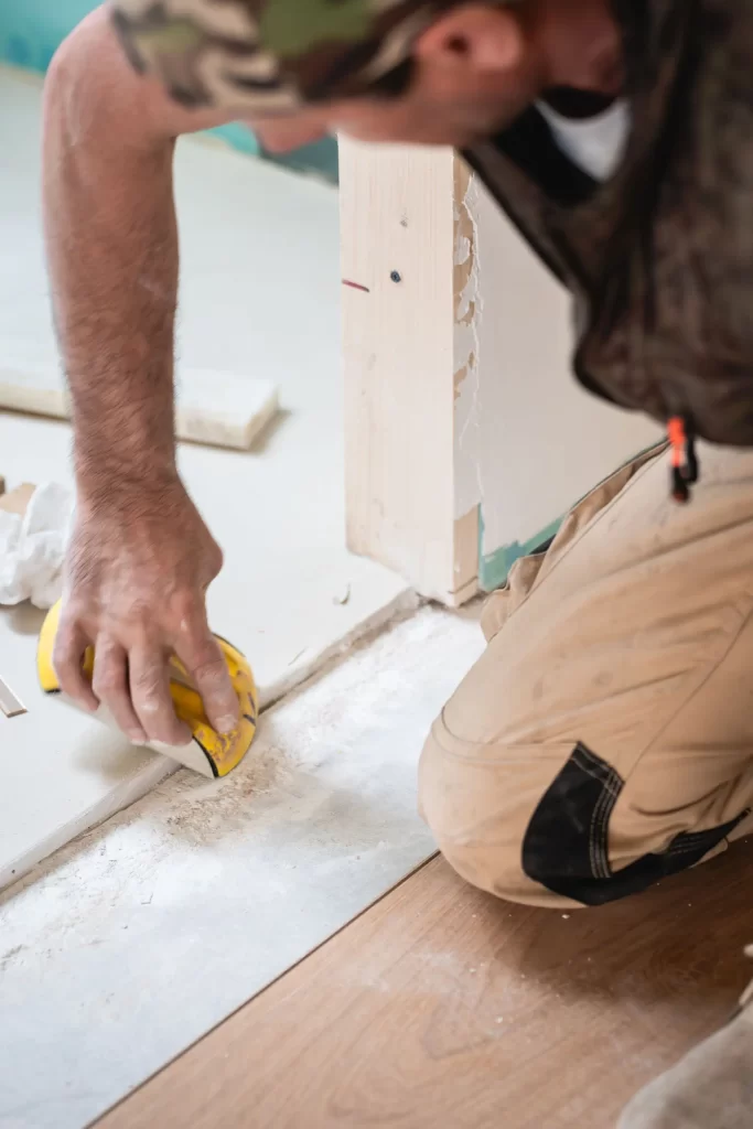 Carpintero profesional preparando la superficie para pegar el parquet en una obra de Rez Estudio en barrio de Chamberí
