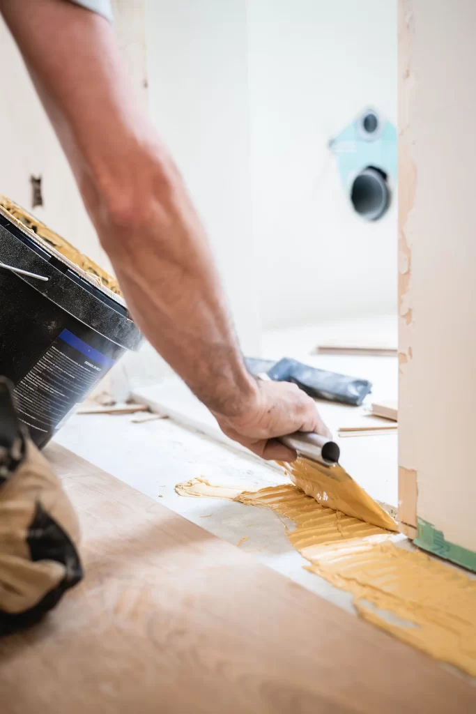 Carpintero profesional montando el parquet con pegamento en una obra de Rez Estudio en barrio de Chamberí