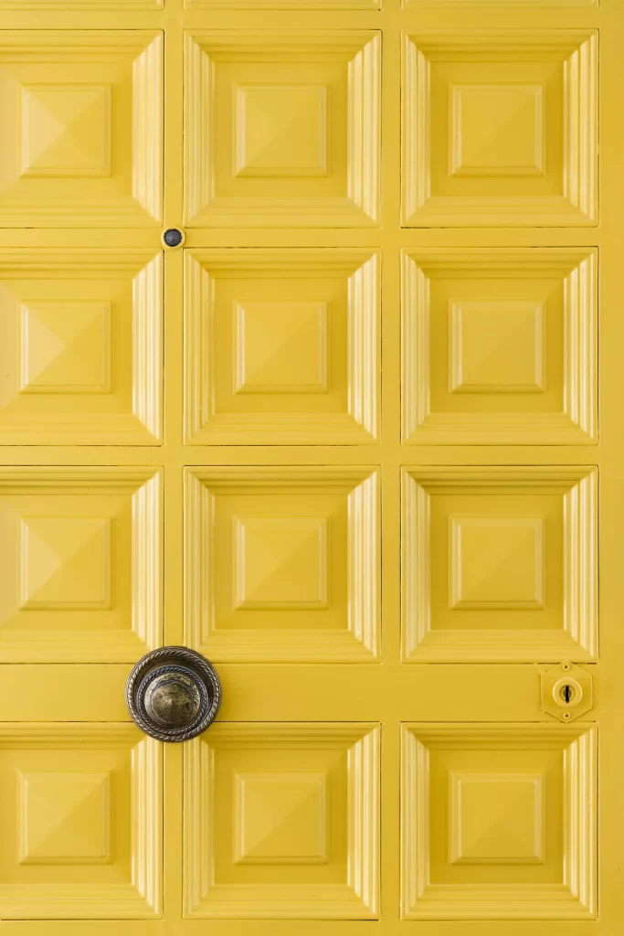 Fotografía de una puerta metálica antigua con relieve modernizadaen color amarillo