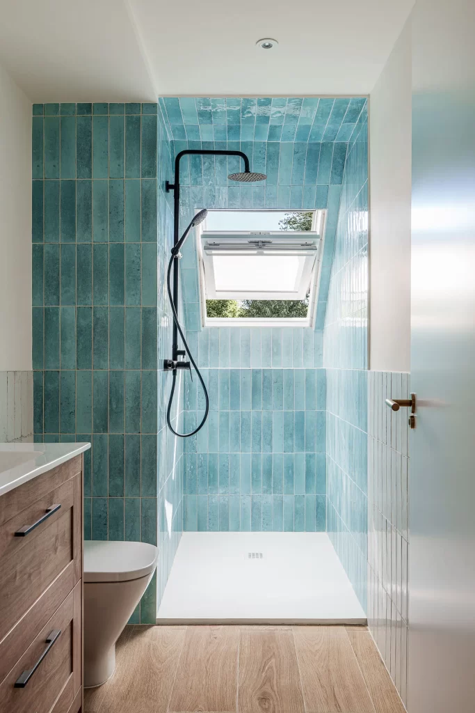 Fotografía de interiores - baño con ducha y ventana velux con azulejos azules