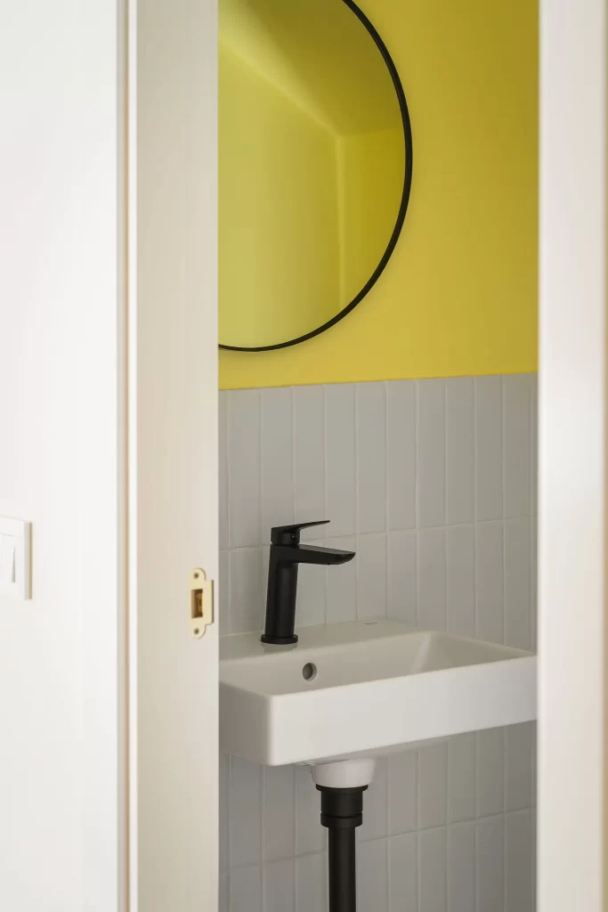 Fotografía de interiores - el aseo reformado, pintado amarillo con azulejos y cerámica blanca